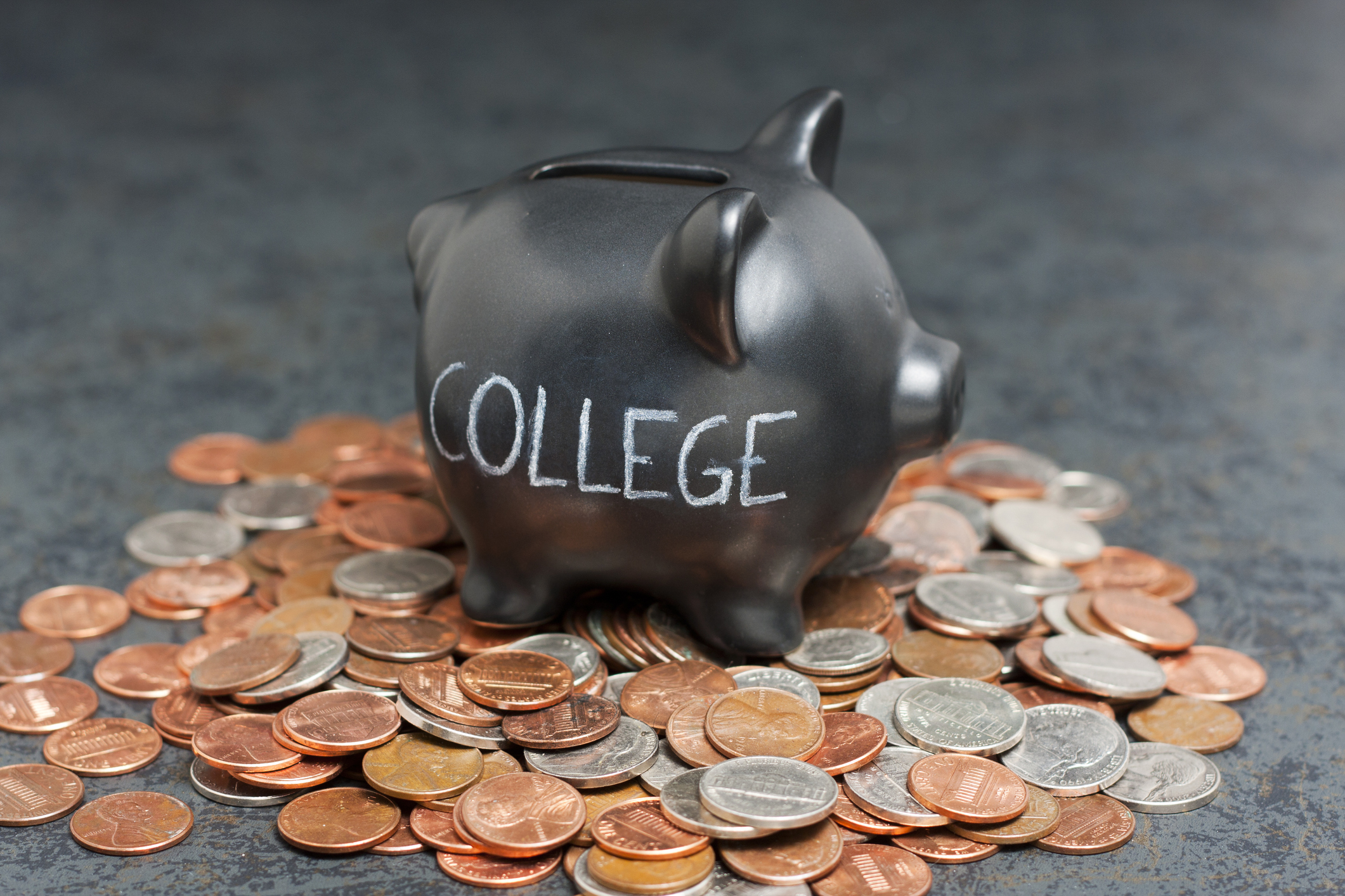 Piggy bank marked college resting on coins