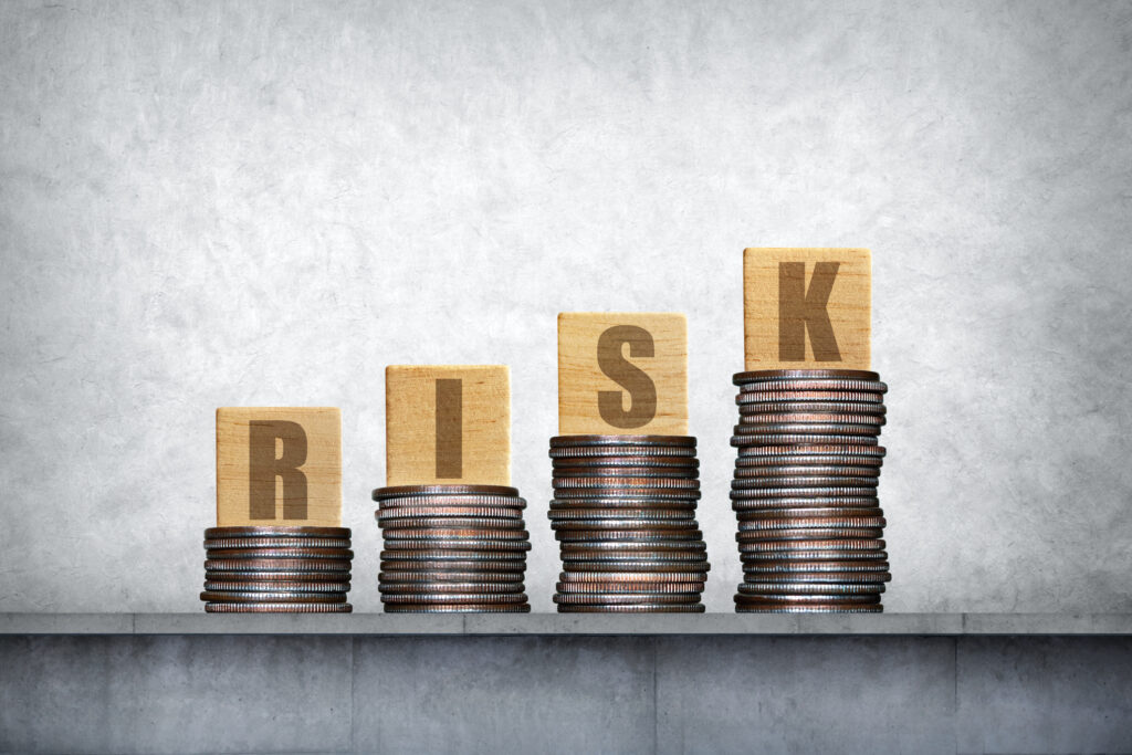 Several stacks of coins with wood blocks on top representing the concept of financial risk.